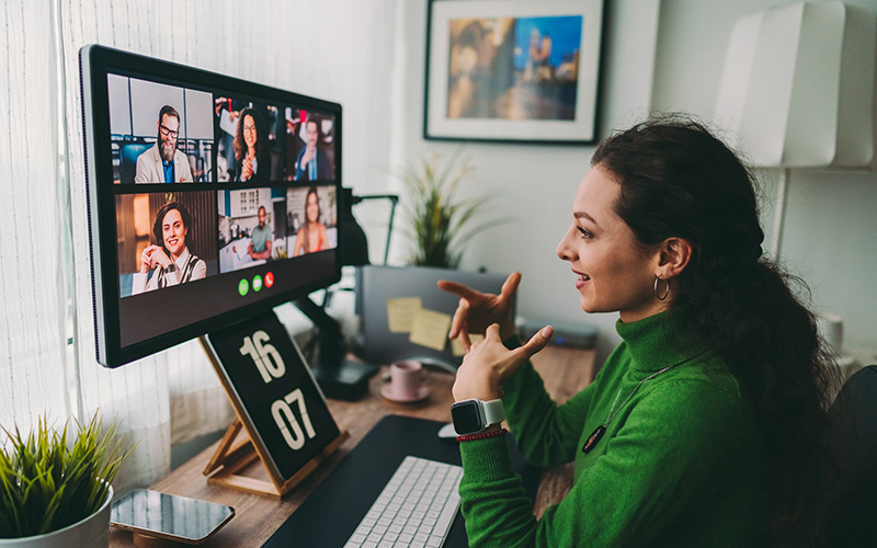  Mulher interagindo com colegas em uma videochamada. A venda de infoprodutos pode ser potencializada com mentorias e cursos online para um contato mais próximo com os clientes.