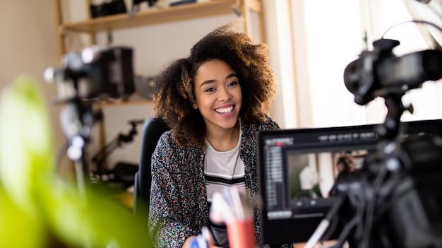 Criadora de conteúdo sorrindo em frente a uma câmera, gravando uma aula para seu curso online , demonstrando engajamento e profissionalismo no ensino digital.