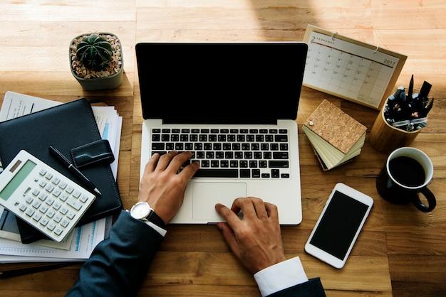 Profissional trabalhando em um laptop, rodeado por cadernos, calculadora e café, mostrando a dedicação e focos necessários para realizar um curso online com eficiência.