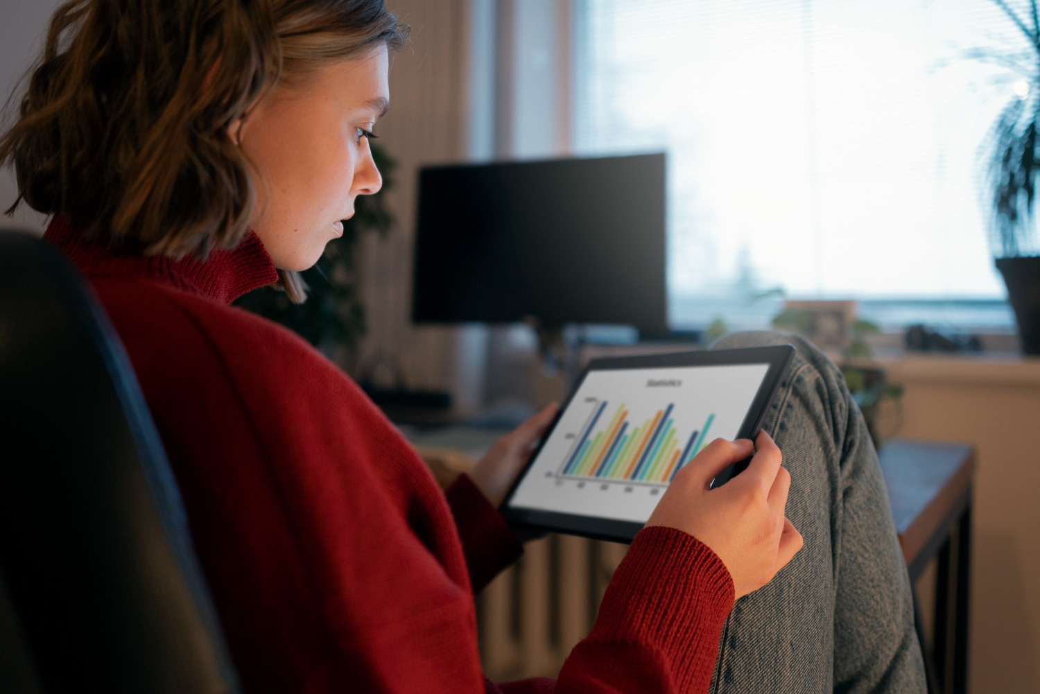 Pessoa segurando um tablet exibindo gráficos e relatórios. Os infoprodutos podem ser analisados ​​com métricas de desempenho para otimização de vendas e engajamento.