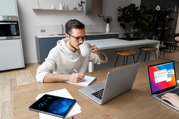 Um homem, em seu escritório, com uma xícara de café ao lado e um laptop aberto, criando textos de "copy" para uma campanha de marketing ou publicidade digital.