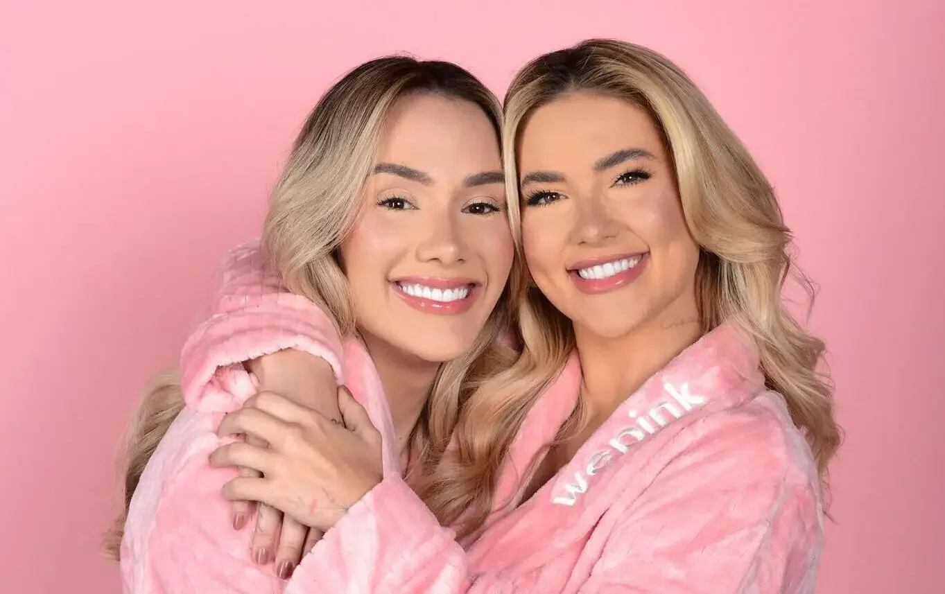 Imagem de Virginia Fonseca e uma amiga usando roupões rosa da Wepink e sorrindo para a câmera. A marca Wepink tem grande sucesso no mercado, e quem quer aprender a criar um negócio de sucesso como esse pode buscar um curso online sobre empreendedorismo e branding.