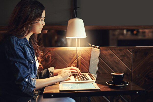 Uma mulher digitando em seu laptop enquanto toma café, provavelmente escrevendo uma "copy" para estratégias de vendas ou marketing digital.